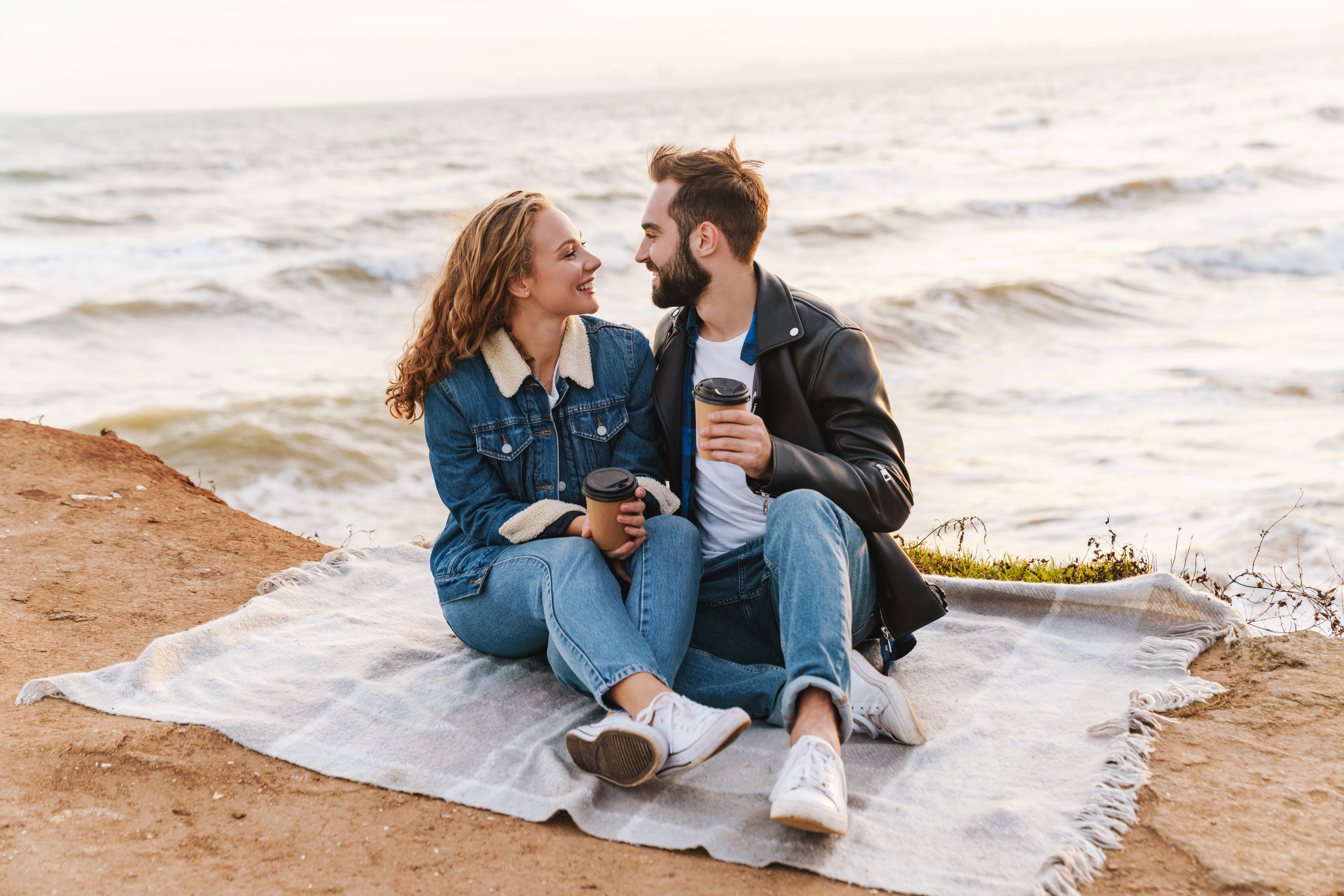 Image of beautiful young couple drinking coffee while walking by