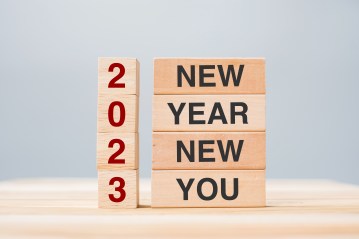 hand holding wooden block with text 2023 NEW YEAR NEW YOU on tab